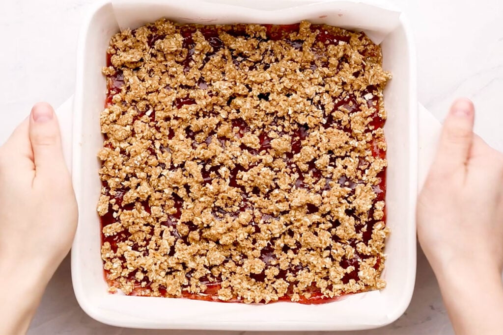 assembled breakfast bars with jam and crumble topping in pan.