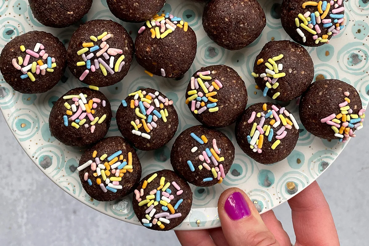 Hand holding plate full of no-cook brownie bites. 