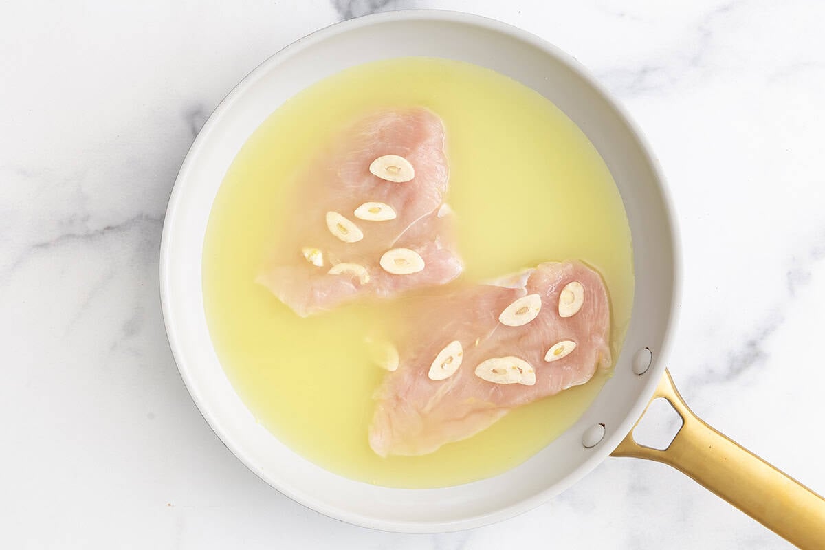Chicken with broth and garlic in pan for chicken for baby. 