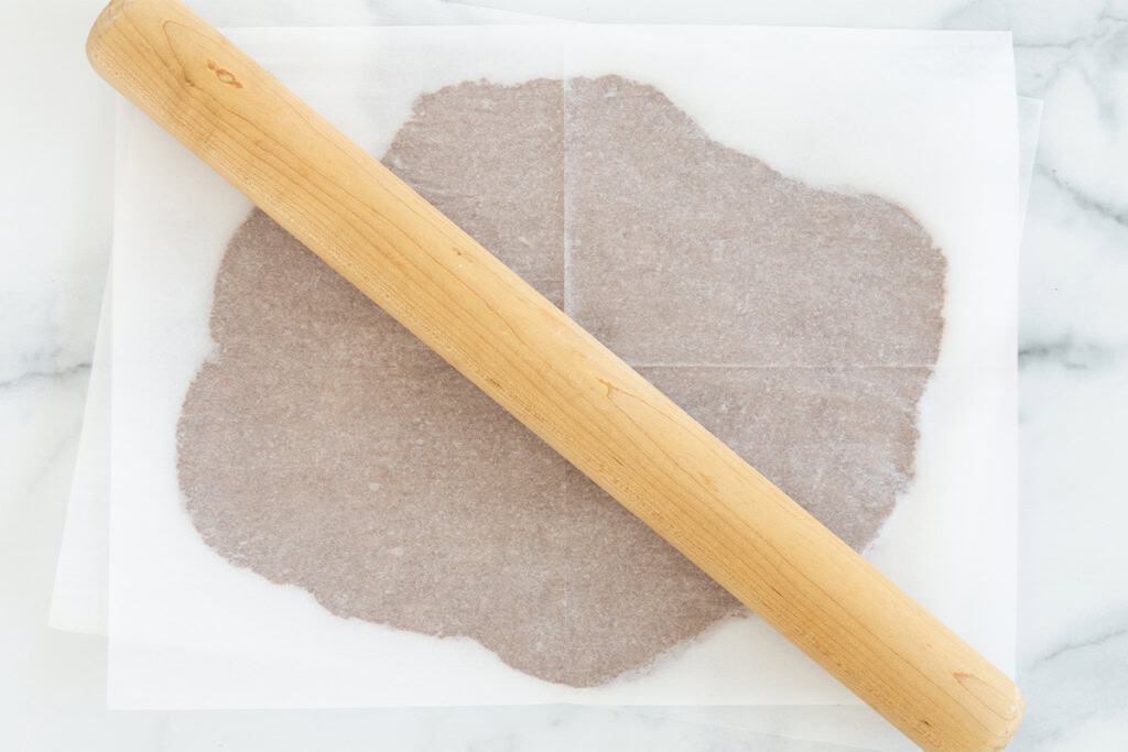 Rolling out dough for chocolate sugar cookies with rolling pin.