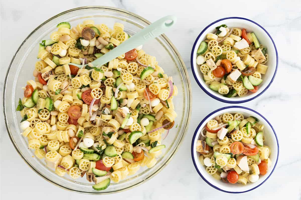 pasta salad with chicken in large serving bowl and two smaller individual bowls.