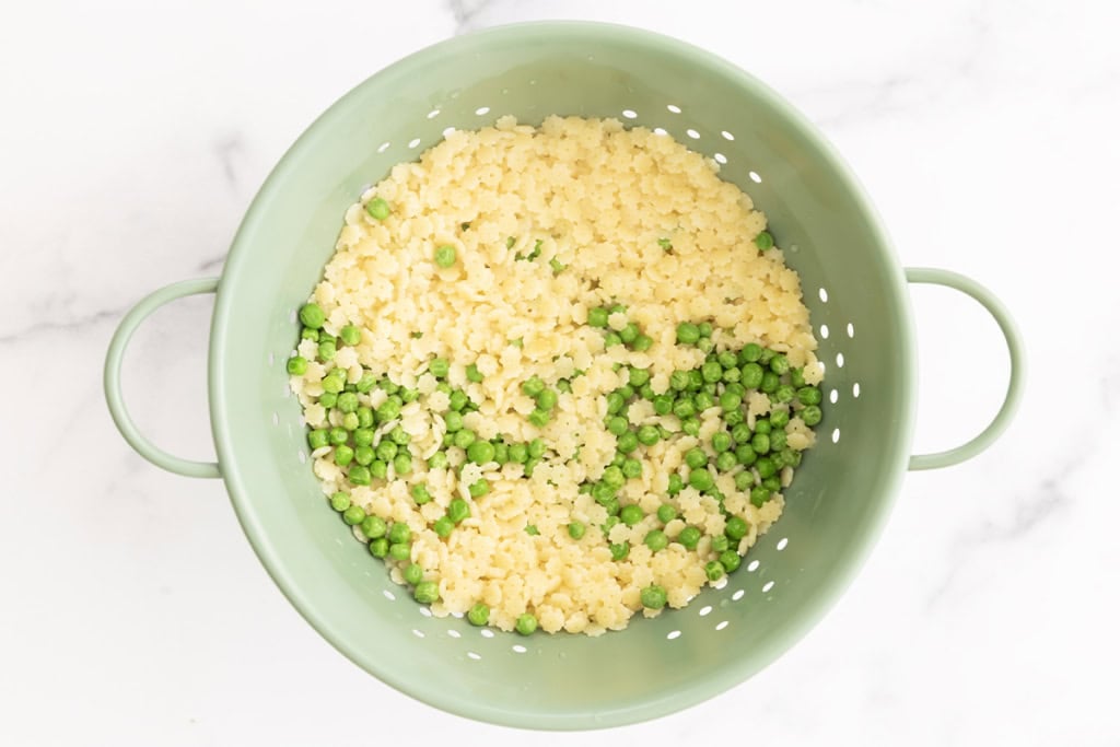 Pasta and peas in strainer for pesto pasta with peas.