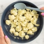 steamed cauliflower on blue plate with spoon.