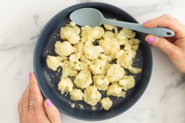 steamed cauliflower on blue plate with spoon.