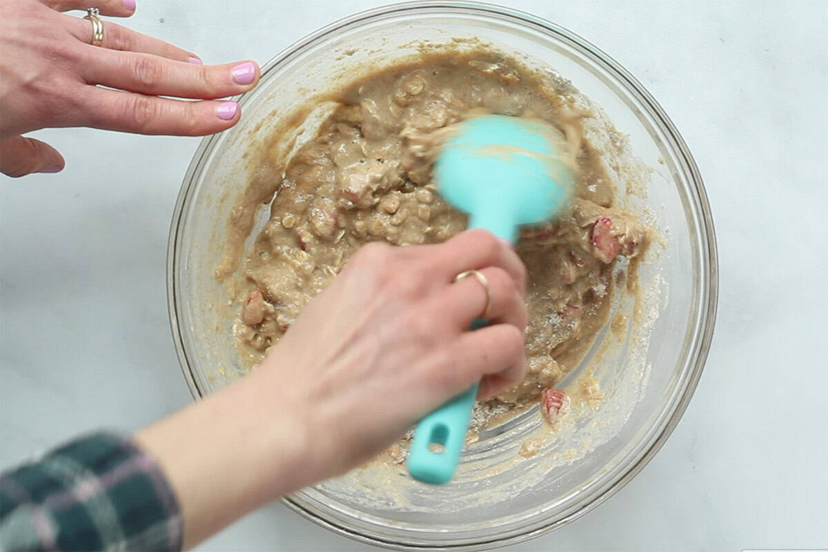 Mixing batter for strawberry muffins in glass bowl.