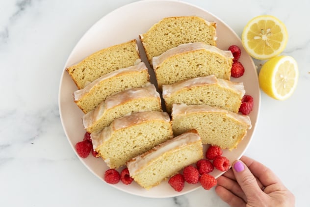 Sliced lemon yogurt cake on plate with berries.