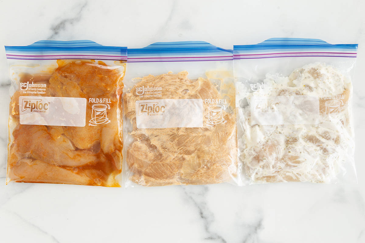 marinated chicken tenders in three storage bags on counter.