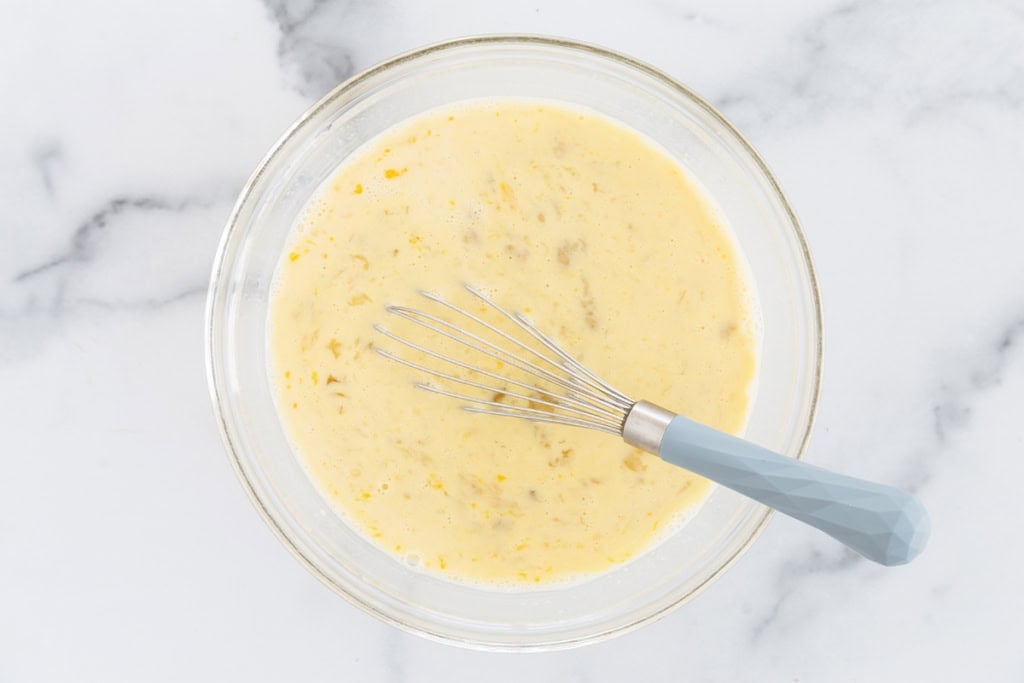 Wet ingredients in glass bowl with whisk.