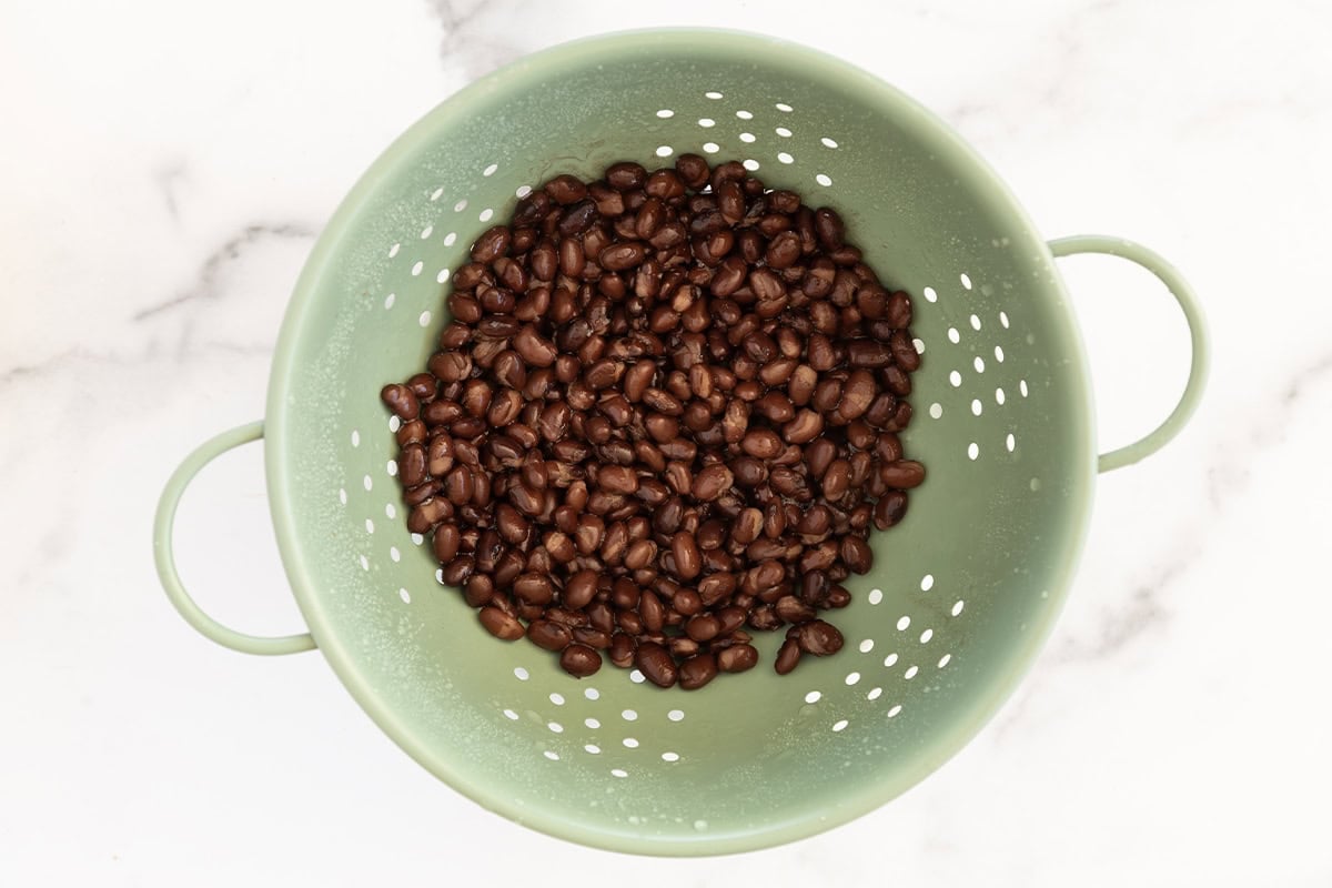 Beans in strainer for vegetarian burrito bowls.
