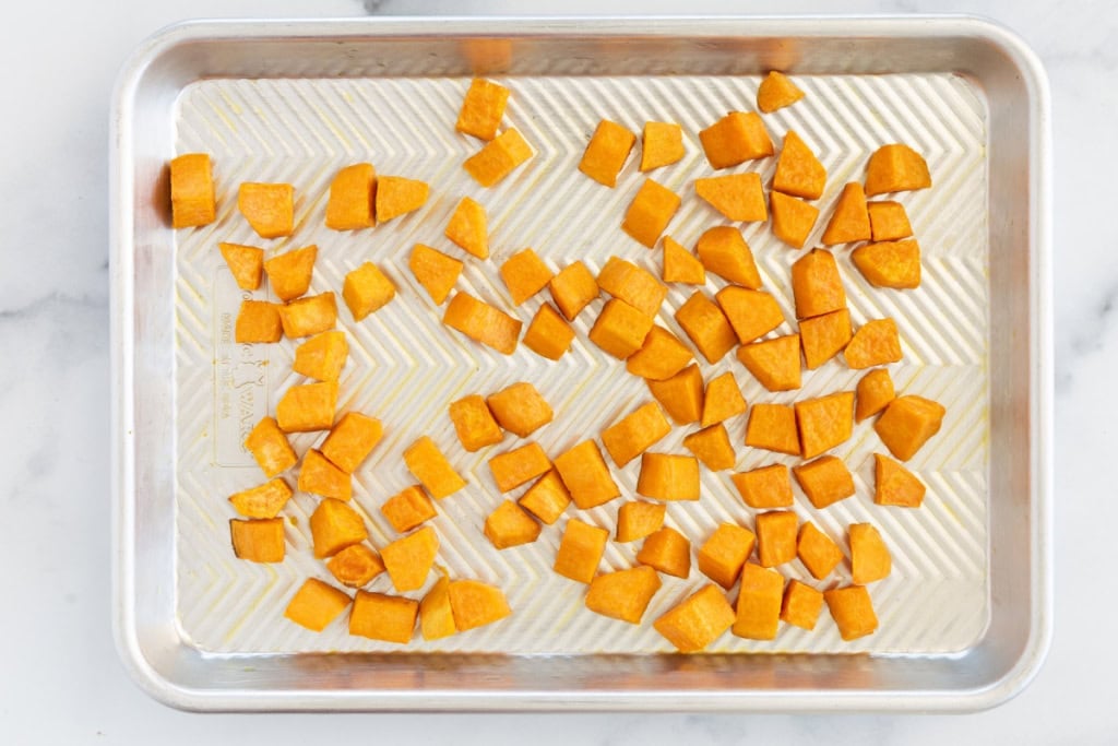 Cubes of sweet potato on baking sheet for burrito bowls.