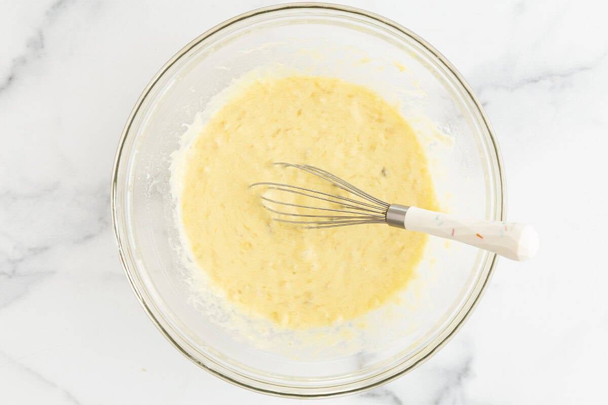 mixing wet ingredients for banana yogurt muffins in bowl.