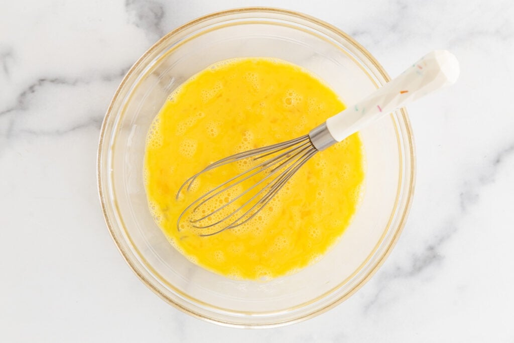 whisking eggs in glass bowl.