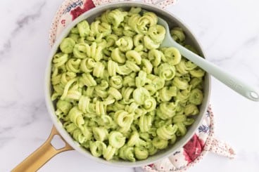 Pasta with pea sauce in pan with spoon.