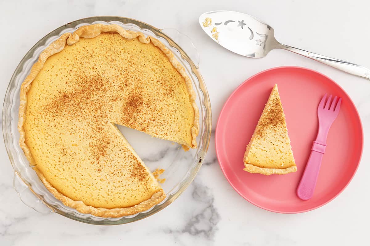 Slice of ricotta pie on pink plate and in pie pan.