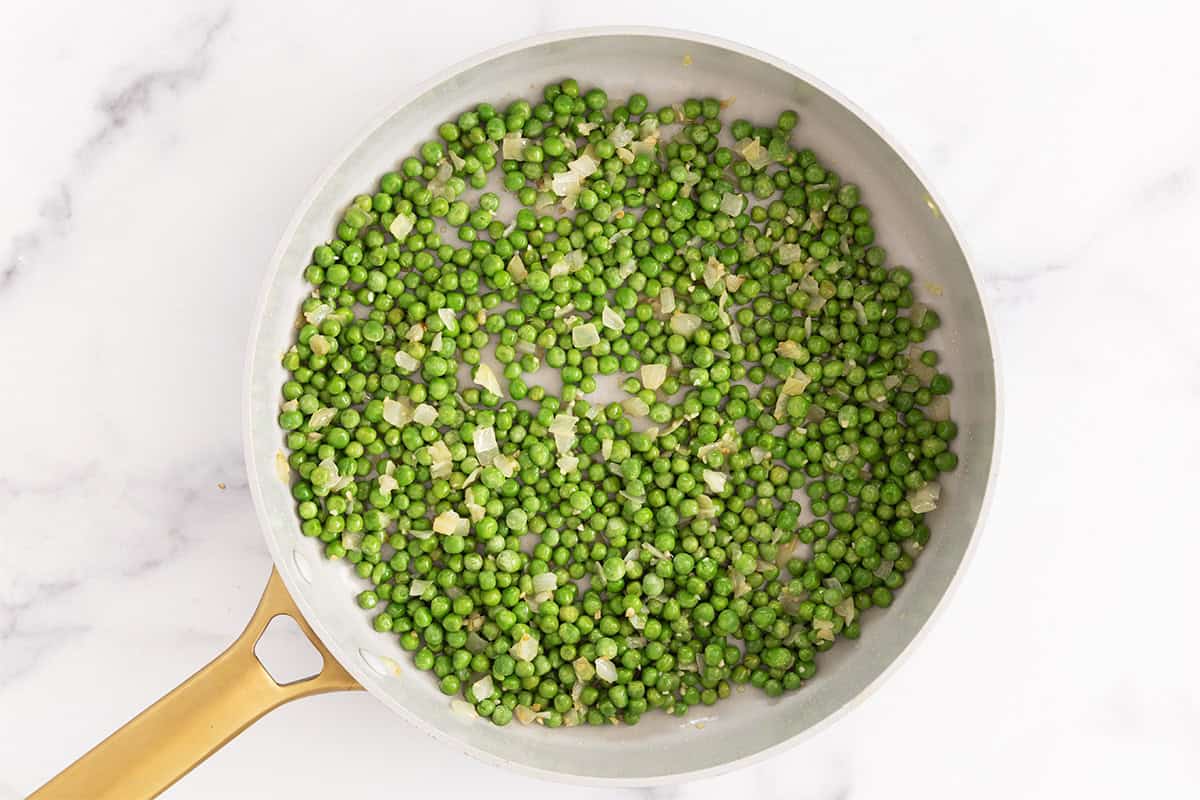 peas and cooked onions in pan for pasta with peas sauce