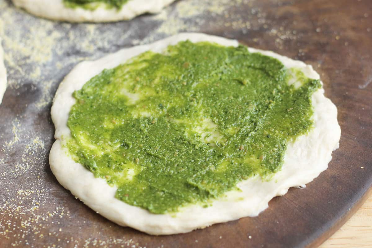 pesto spread on pizza dough.