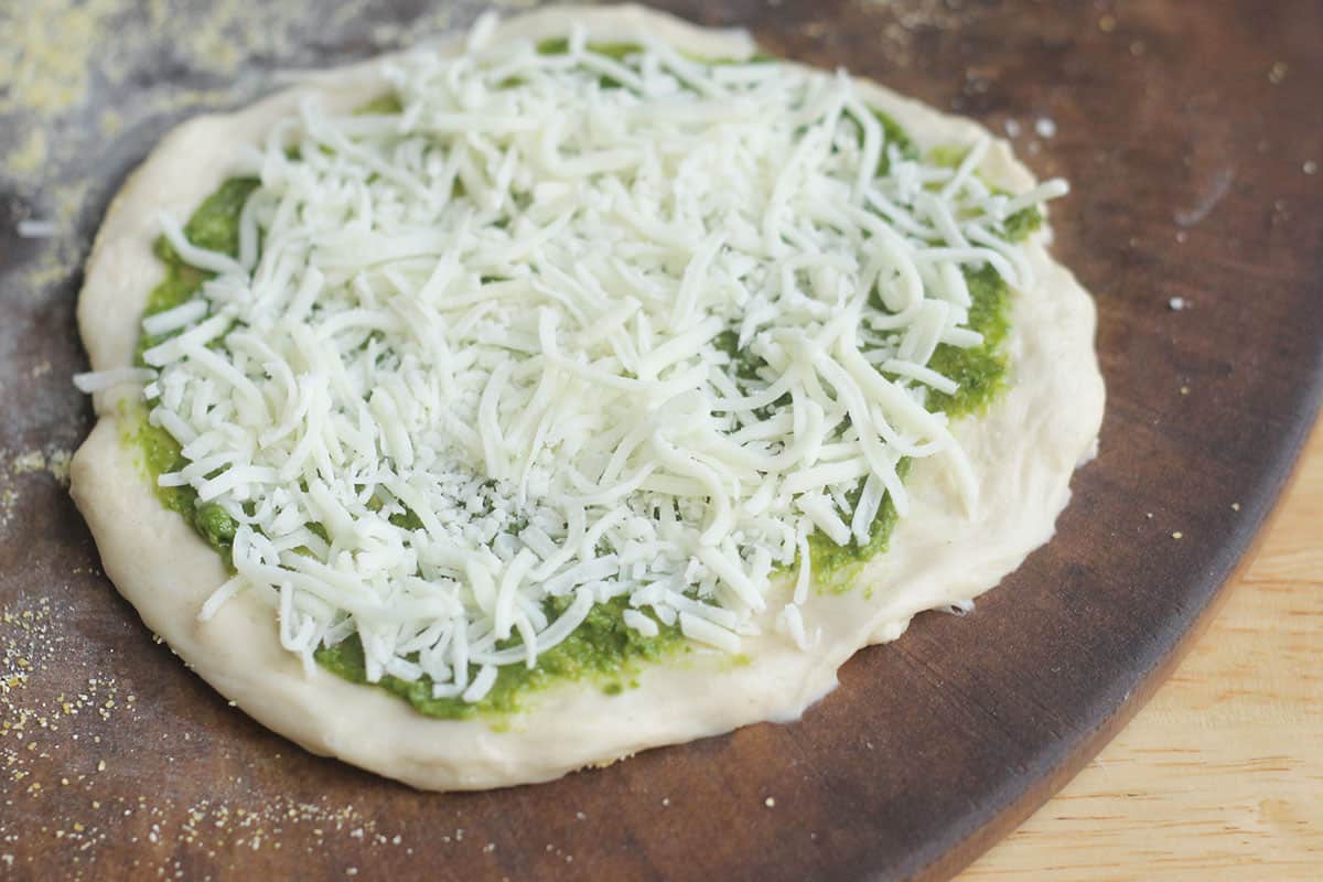 pesto pizza with shredded mozzarella cheese.