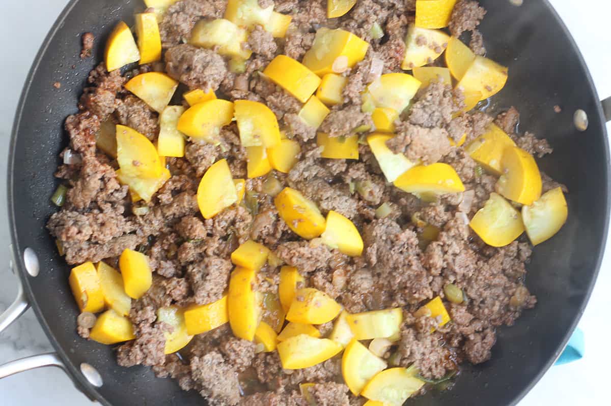 beef and summer squash in black skillet.