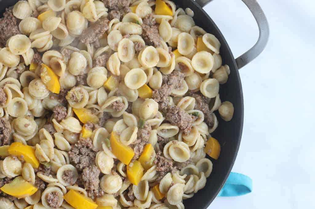 pasta with summer squash and beef in black skillet.