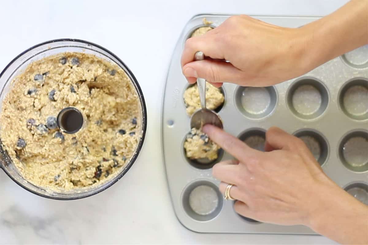 adding batter for blueberry banana muffins to muffin pan.