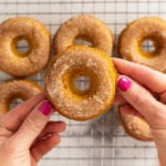 Hands holding pumpkin donut.