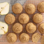Pear muffins on cooling rack with pear halves on side.