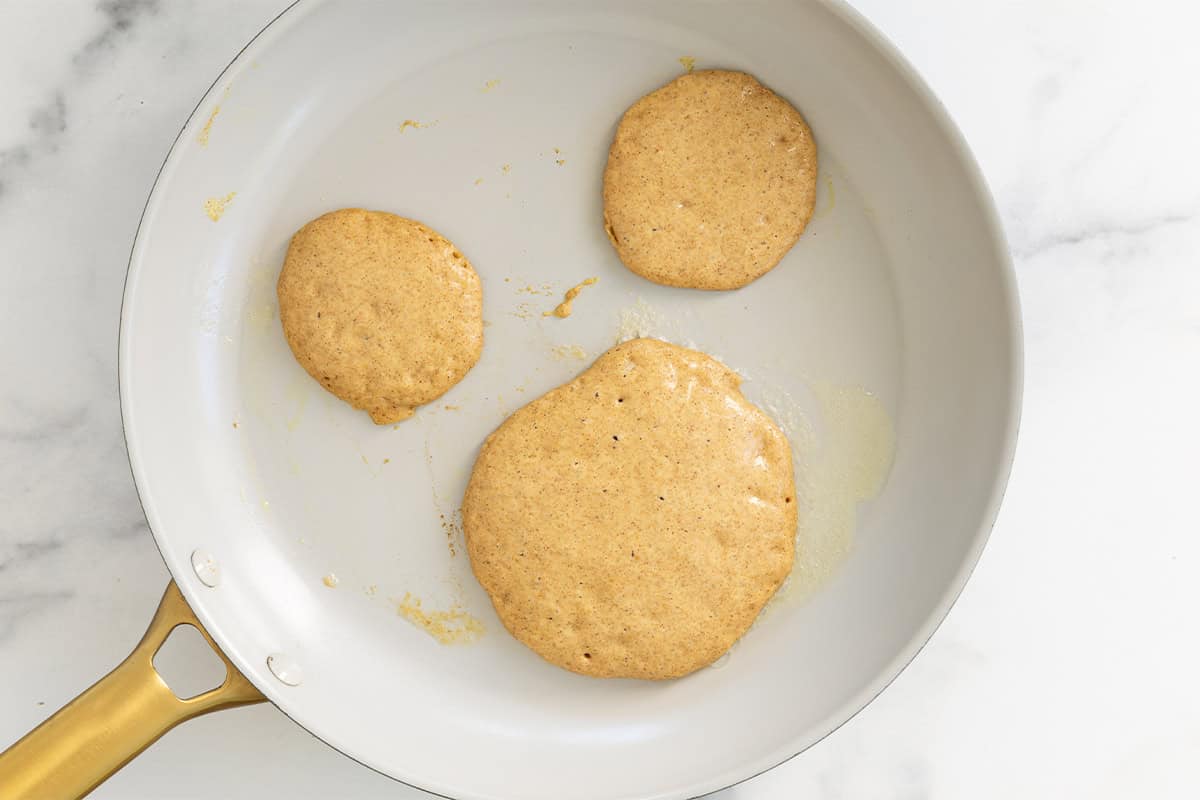 Pumpkin protein pancakes in pan before flipping.