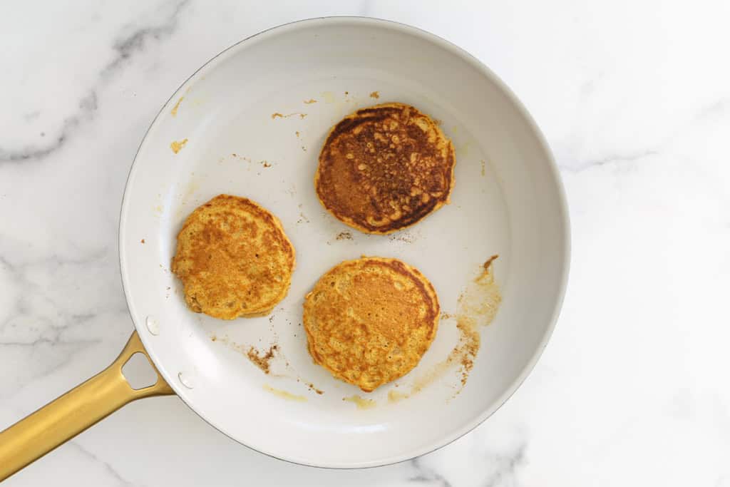 Pumpkin protein pancakes in pan after flipping.