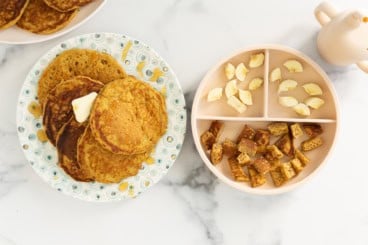 Pumpkin protein pancakes on two plates with sides.