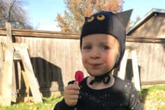 toddler in bat hat with lollipop.
