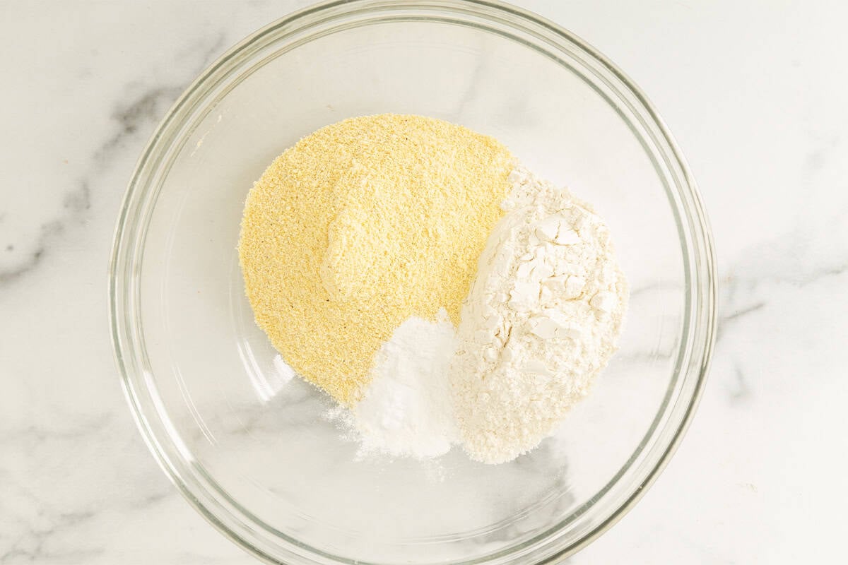 Dry ingredients for cornbread muffins in glass bowl.