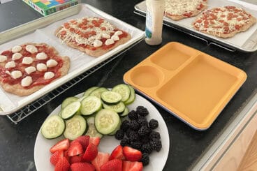 pizza with plate of produce on counter.