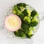 Broccoli and cheese sauce on plate.