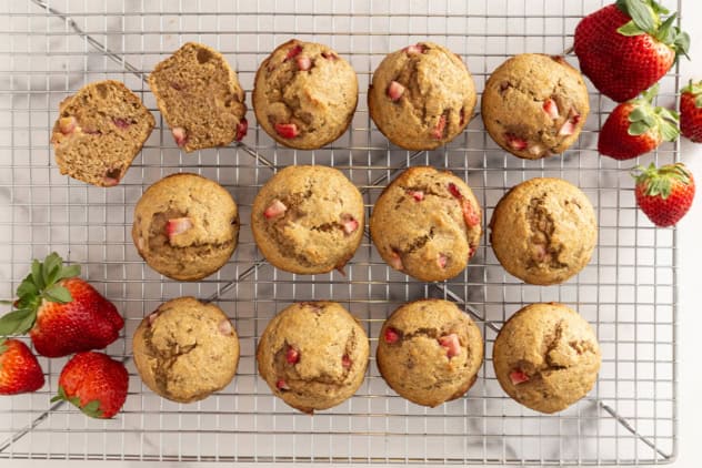 Strawberry banana muffins on cooling rack with strawberries on side.