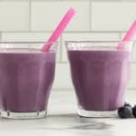 Blueberry Yogurt Smoothie in two glasses with pink straws.
