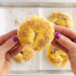 Hands holding cottage cheese bagel.