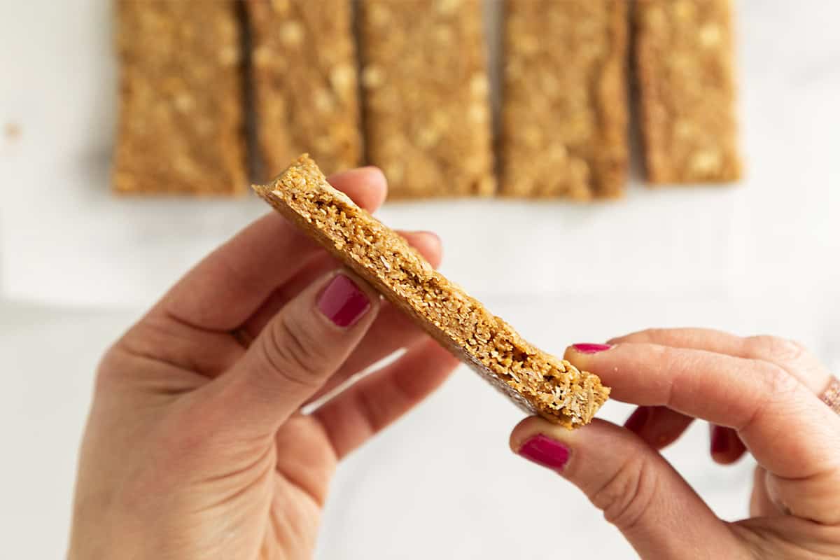 Hands holding crunchy granola bar.