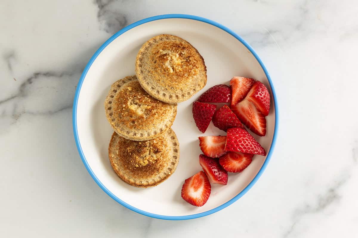 Pizza uncrustables on plate with strawberries.
