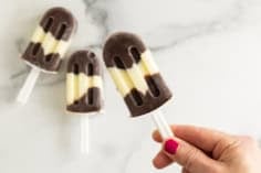 Pudding pops on countertop with hand holding one.