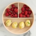 Rice balls on kids plate with raspberries.
