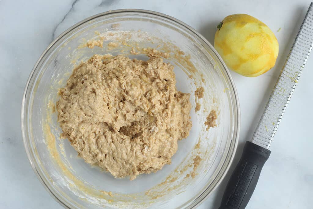 batter for lemon blueberry muffins in bowl with lemon.