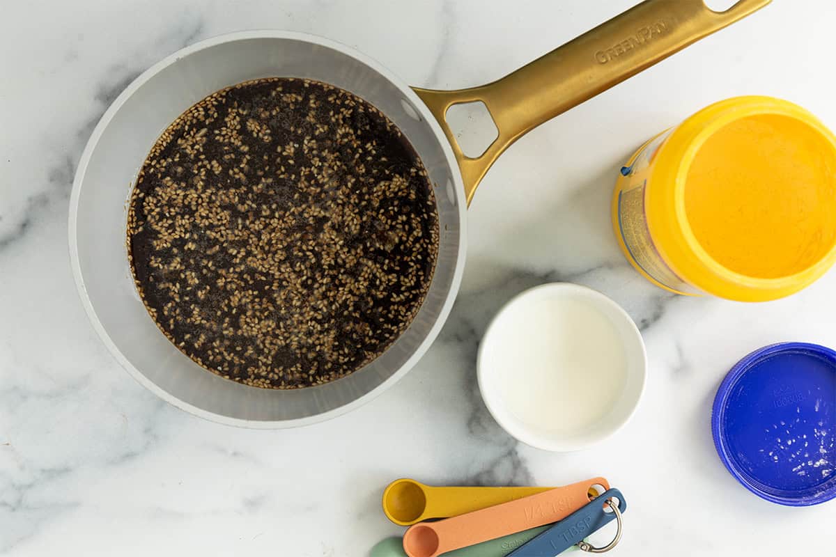 Teriyaki sauce in pan with measuring cups on side.