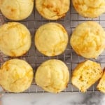 Cheese muffins on cooling rack with one muffin cut in half.