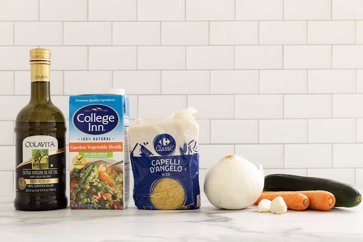 Ingredients for vegetable noodle soup on countertop.