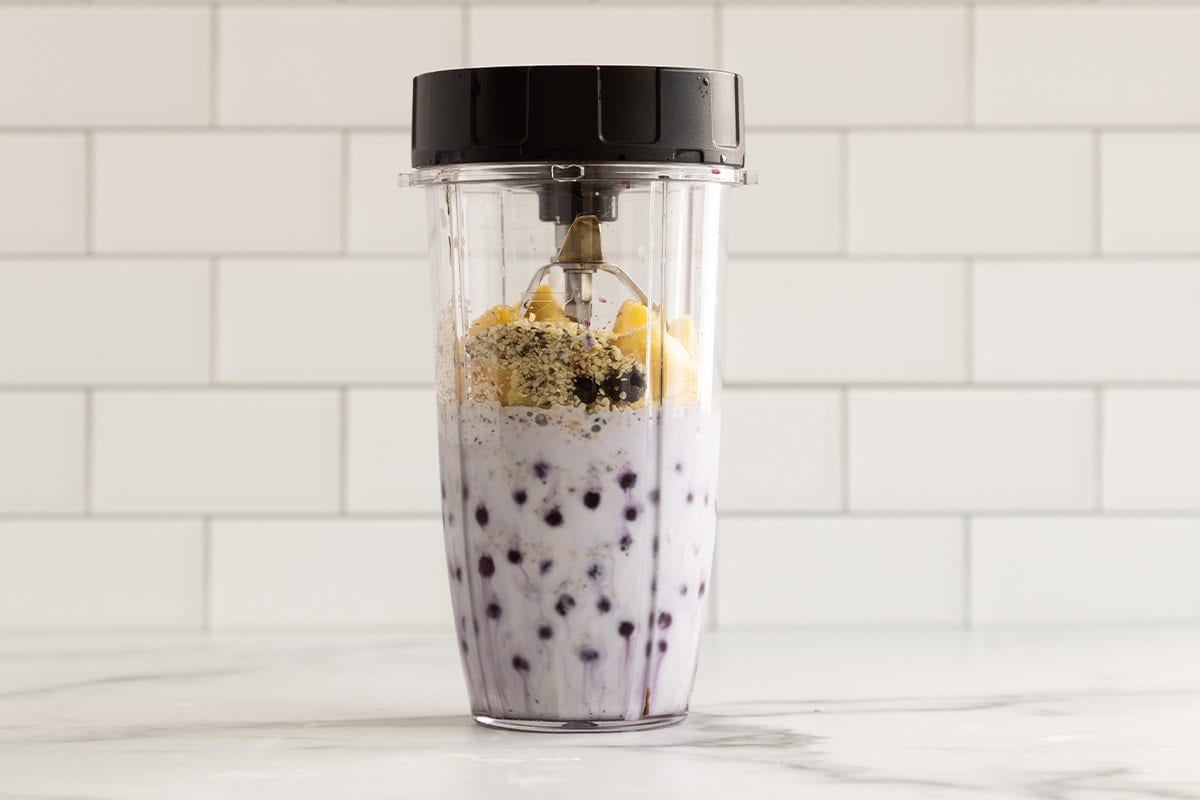 Blueberry smoothie in blender before blending.