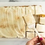 Pumpkin bars with frosting, hands holding bar on spatula.