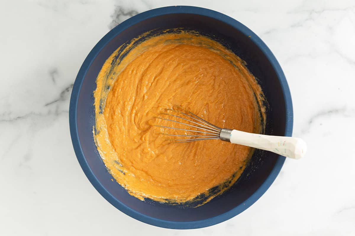 Wet ingredients in blue bowl for pumpkin bars.
