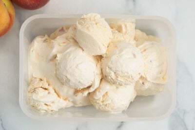 scoops of fresh peach ice cream in container.