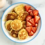 Almond flour pancakes on plate with strawberries and syrup.