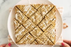 Hands holding white plate with apple oatmeal bars.